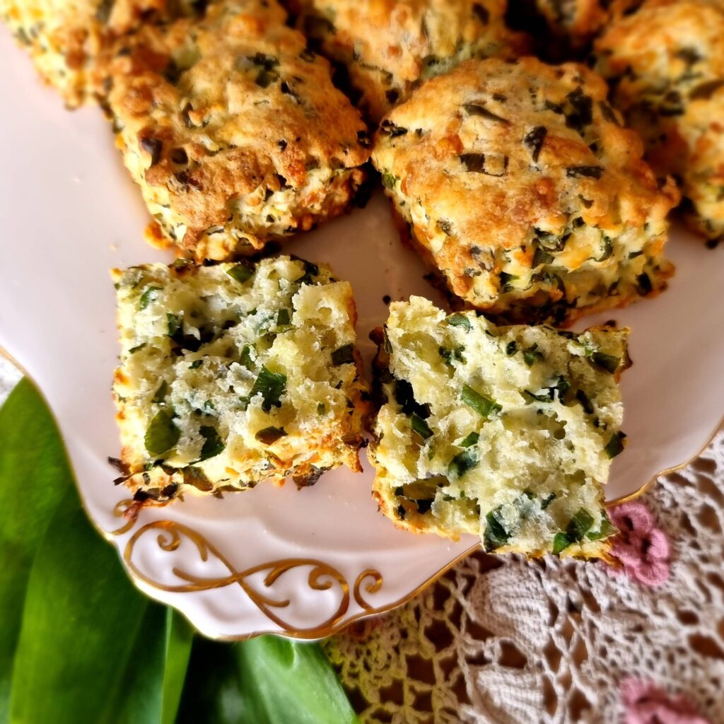 green tinged wild garlic and cheese scones on a pink platye. one scone is split open to show the inside
